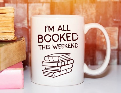 image is a stack of books and coffee mug that reads "I'm all BOOKED this weekend"